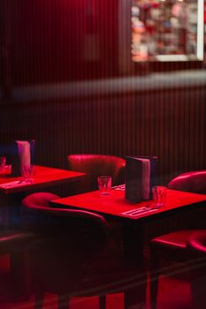 Warm interior of a restaurant with red lighting in London, featuring elegant dining tables.