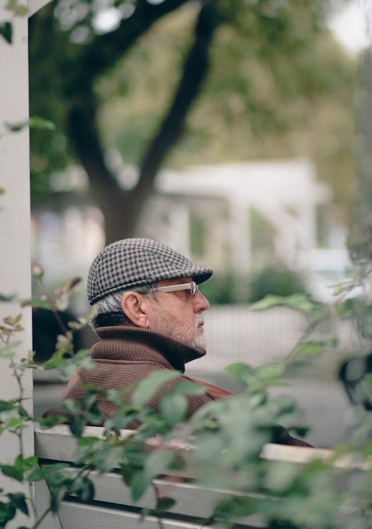 Old Bearded Man In Hat Sitting On Bench In Park