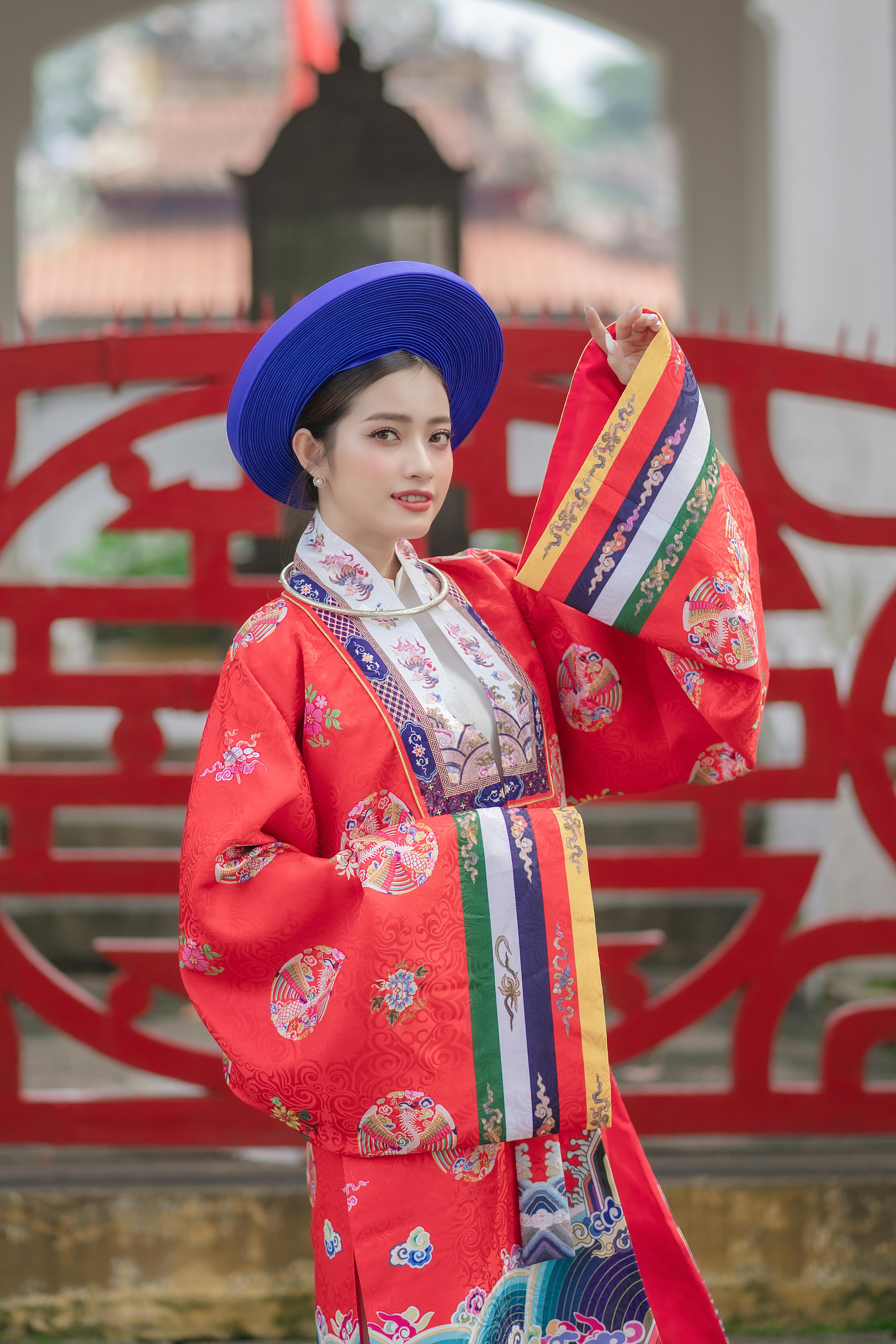 Woman in vibrant traditional Vietnamese costume posing outdoors.