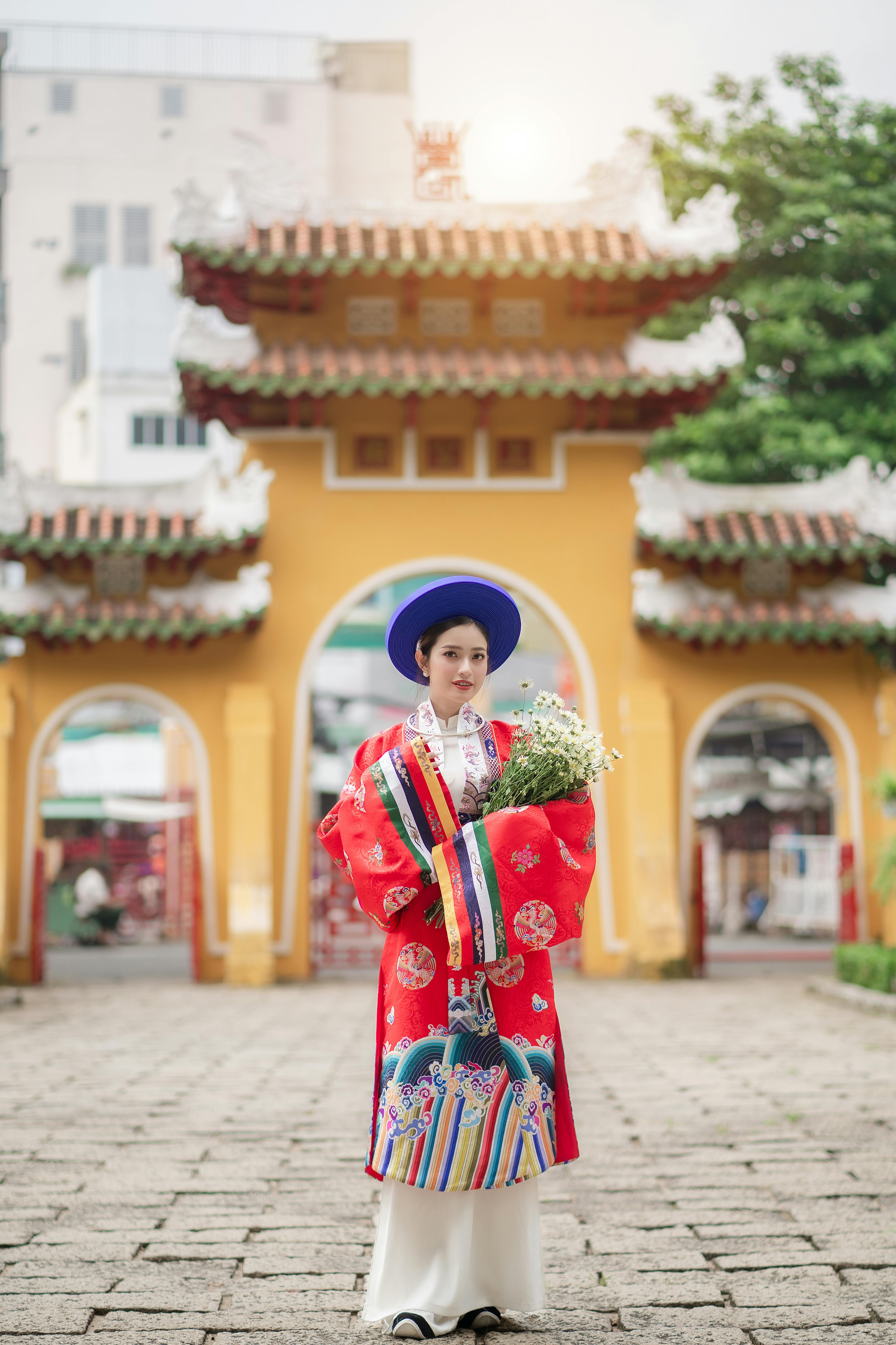 model in traditional vietnamese ao nhat binh costume with a bunch of chamomile flowers