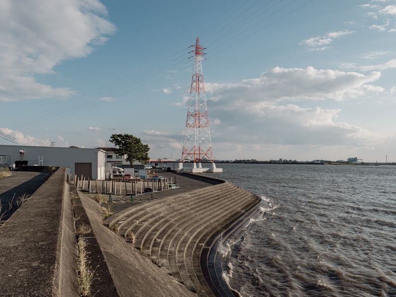 Power lines running beside a seawall as waves break against the shore. Photo by Huu Huynh on Pexels.