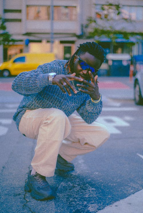 Man in White Pants and Blue Sweater Posing on a Street