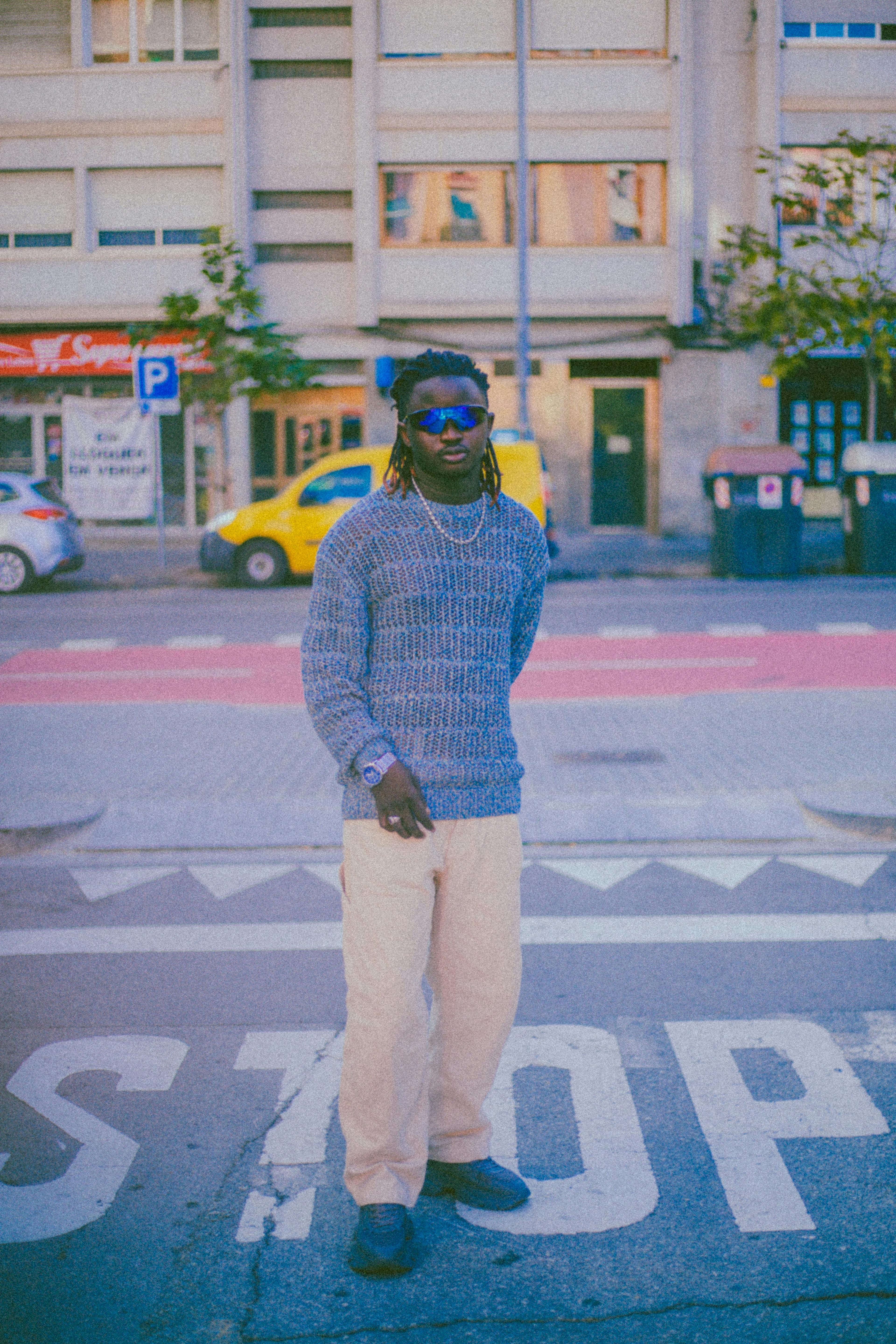 Fashion-forward man stands confidently on city street, embodying urban style.