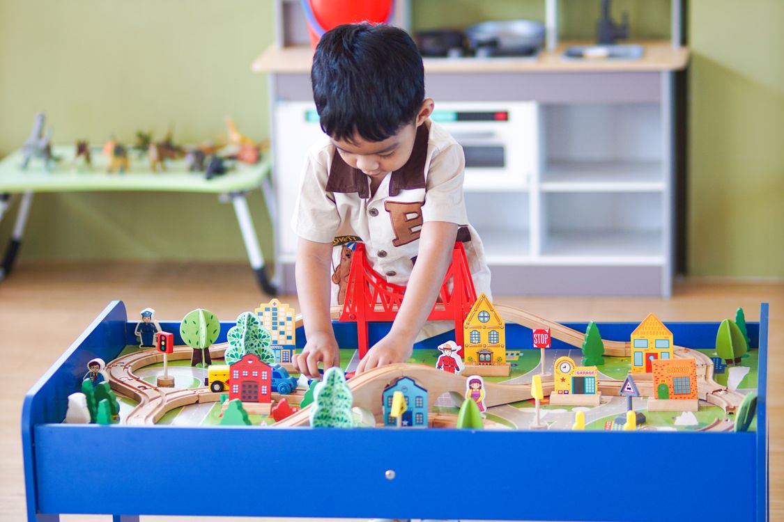 Free Young boy playing with a colorful wooden toy set, enhancing creativity and learning indoors. Stock Photo