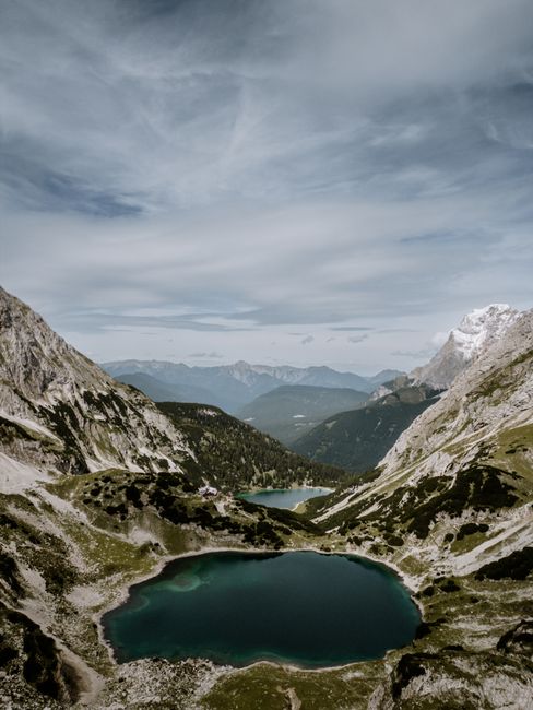 Stunning view of a tranquil alpine lake surrounded by rugged mountains under a cloudy sky.