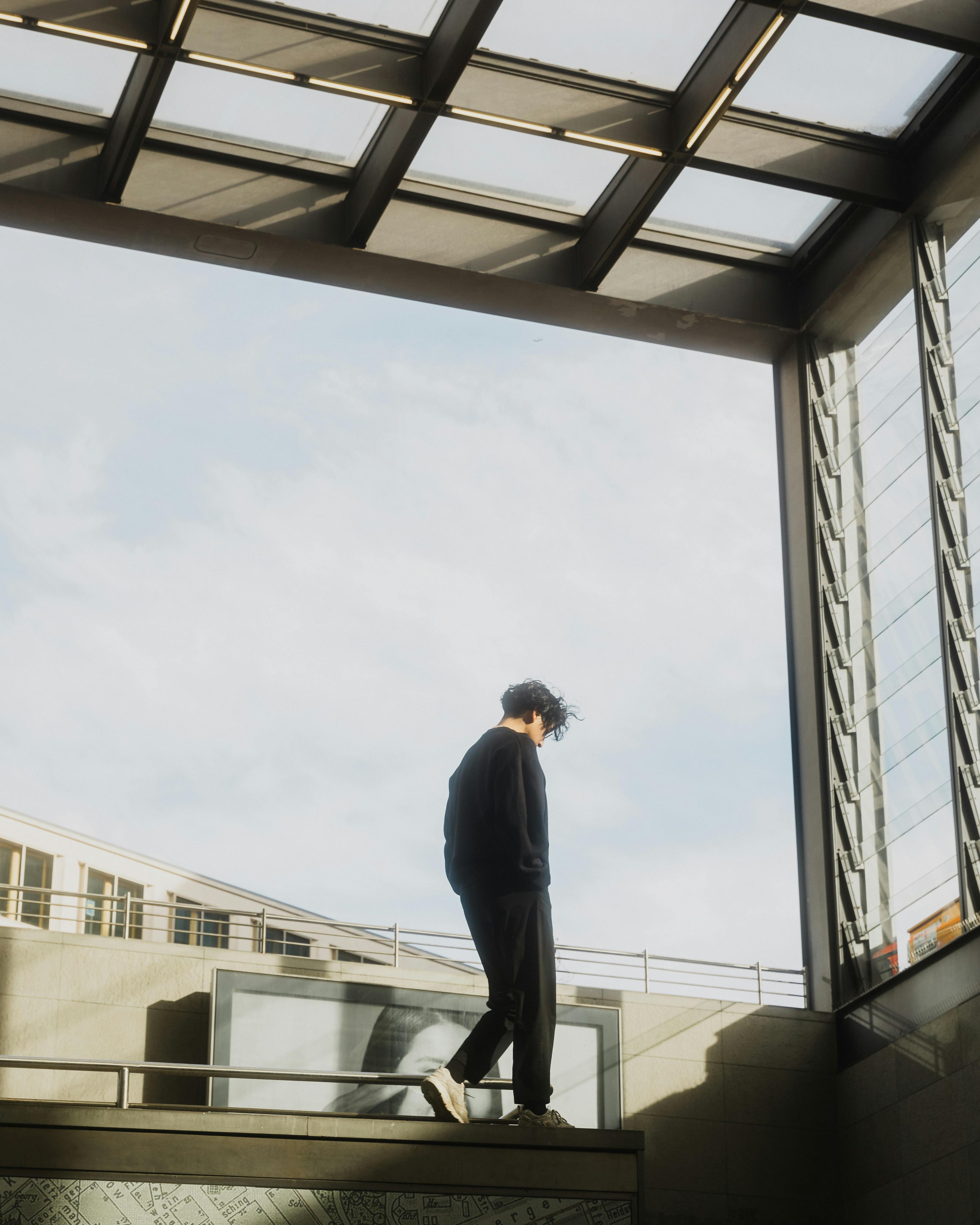 A solitary figure walking in a sleek Berlin urban setting on a bright day.
