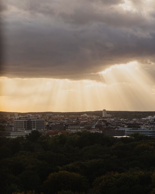 Free Stunning cityscape of Berlin at dusk with dramatic sunbeams piercing through clouds. Stock Photo
