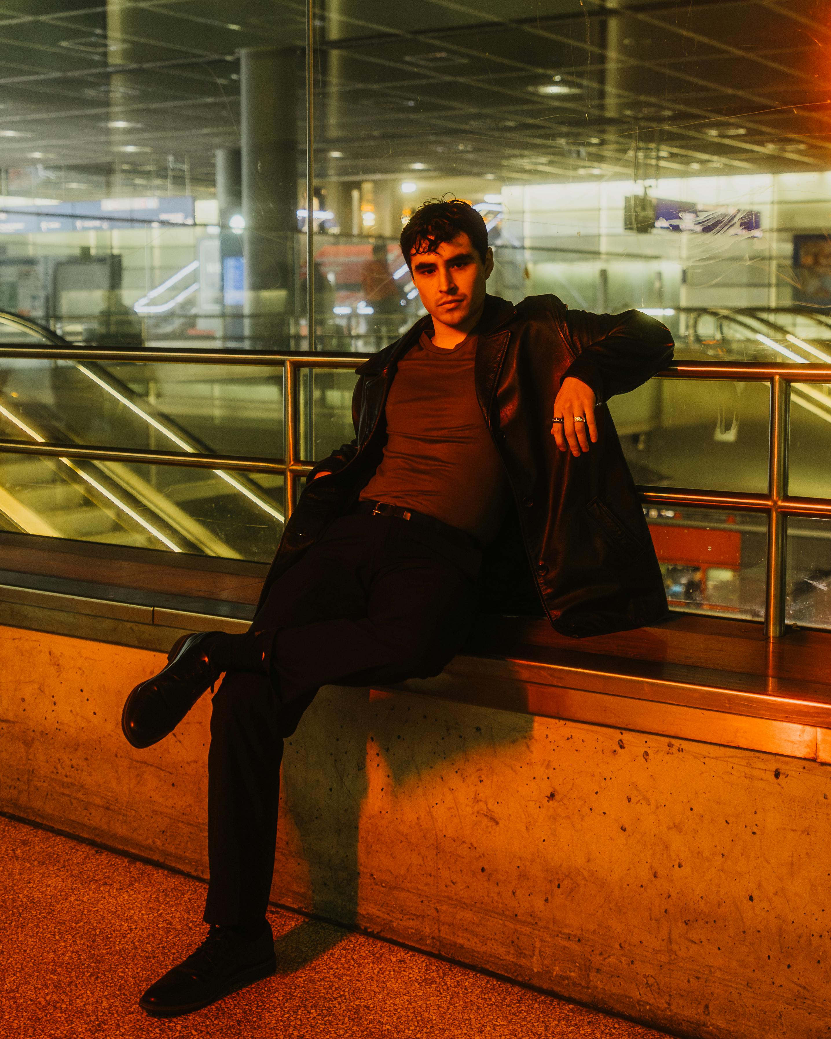 Stylish man in leather jacket sitting in Berlin metro station, showcasing urban fashion vibe.