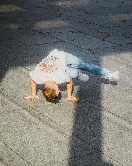 A skilled breakdancer performs a unique move on a Berlin sidewalk.