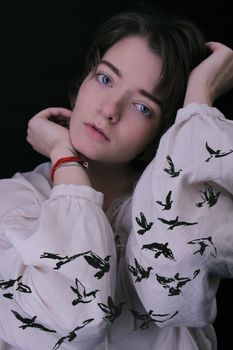 一名女子身着鸟纹衬衫，在暗色背景前摆姿势的特写照