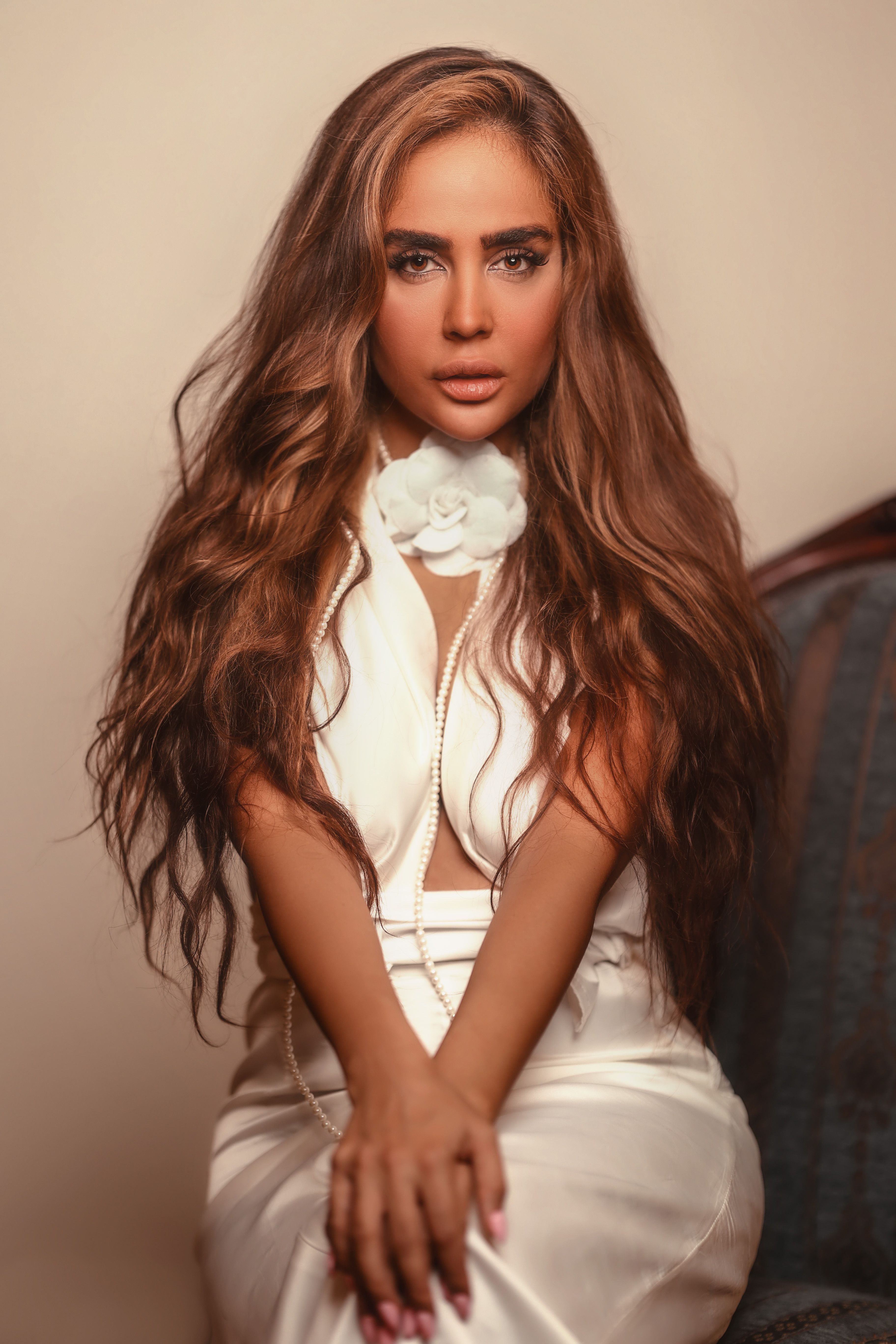 Elegant portrait featuring a woman with long brown hair in a chic white outfit, showcasing fashion and beauty.