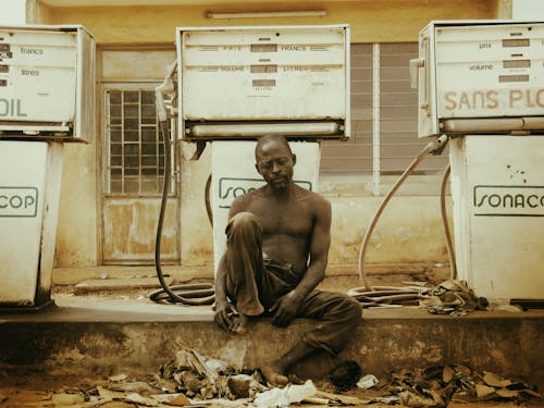 A man sitting on the ground next to a gas station