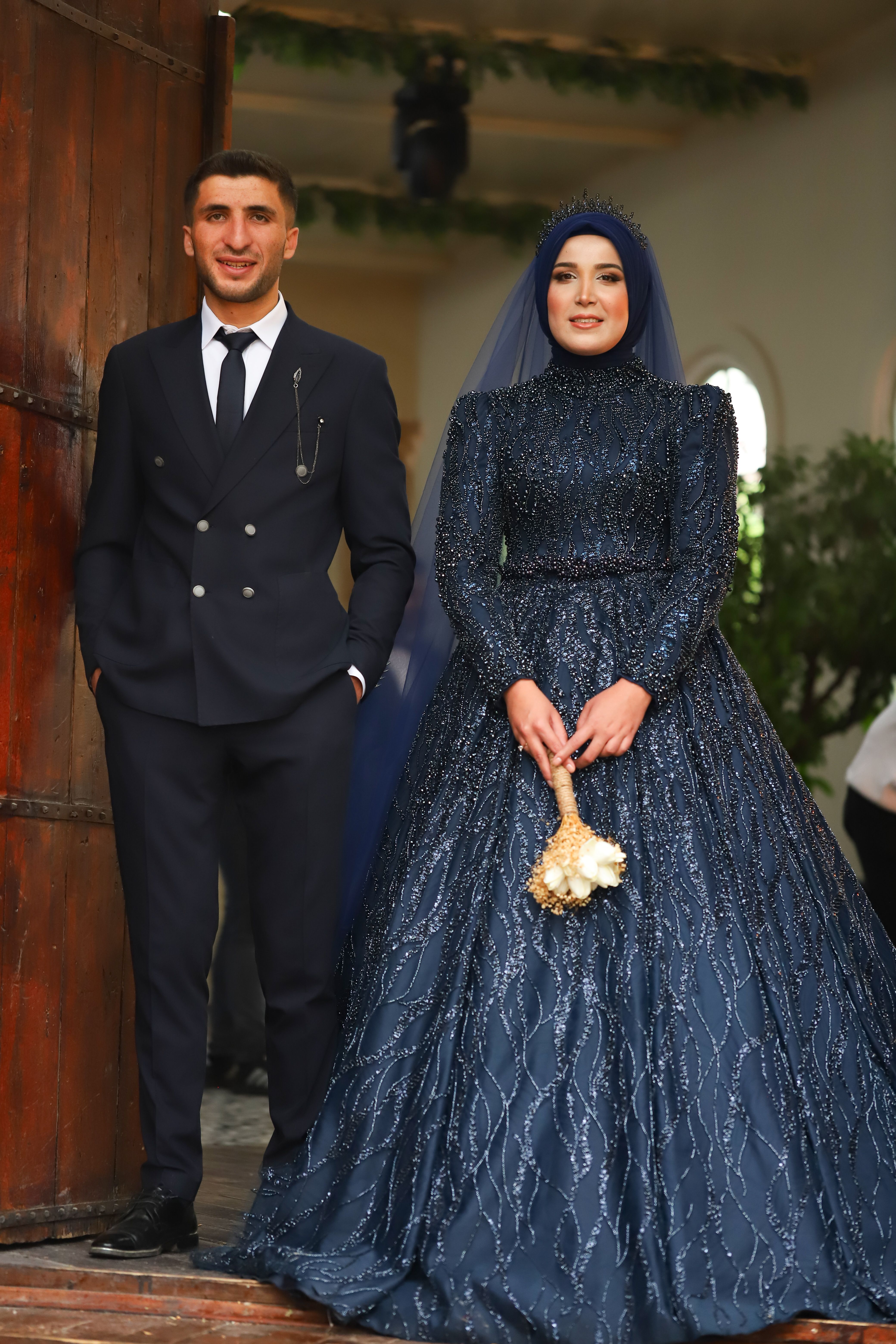 Stylish portrait of a Middle Eastern couple in wedding attire, standing gracefully.