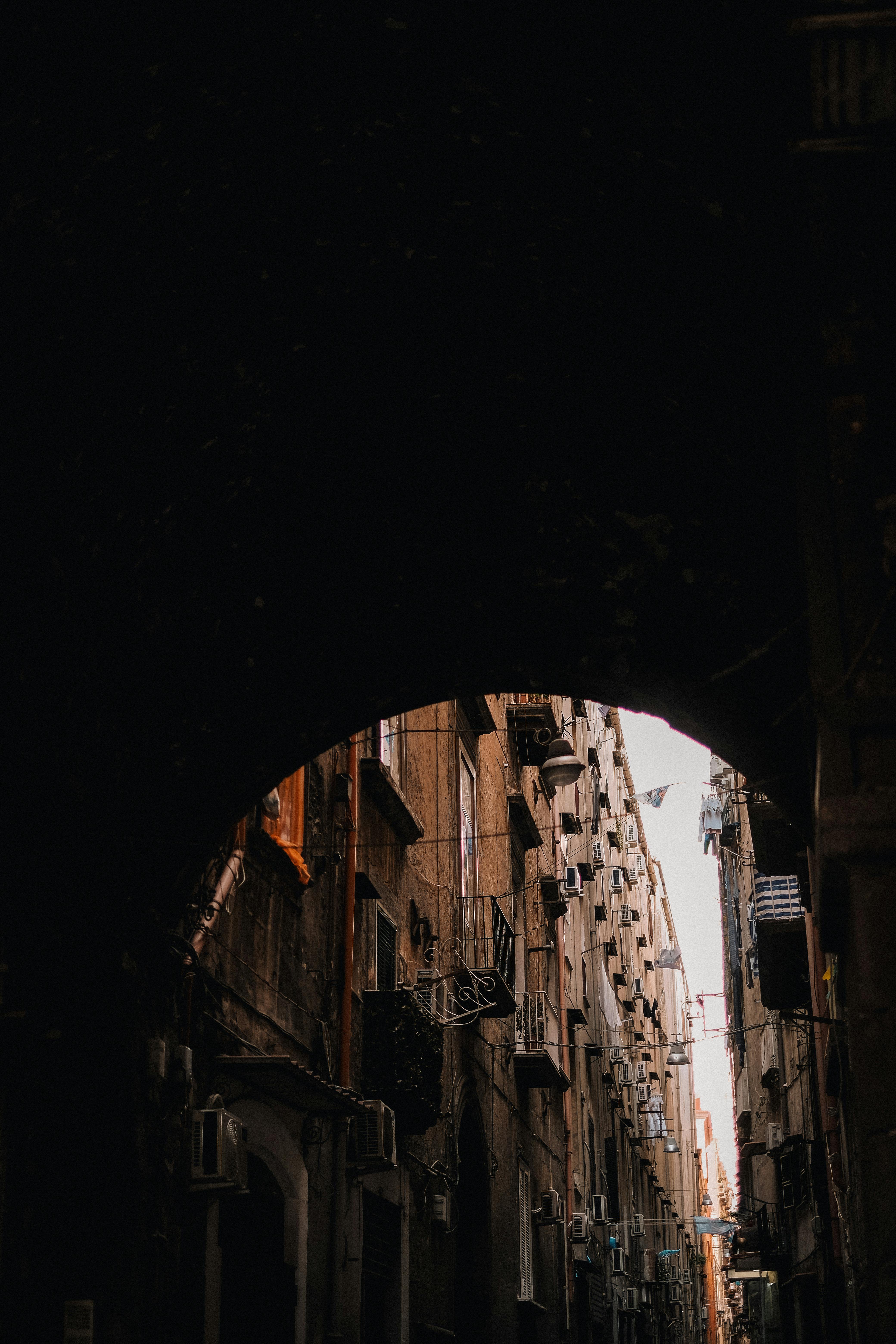 Low-angle view of a narrow urban passageway framed by historic building arches.