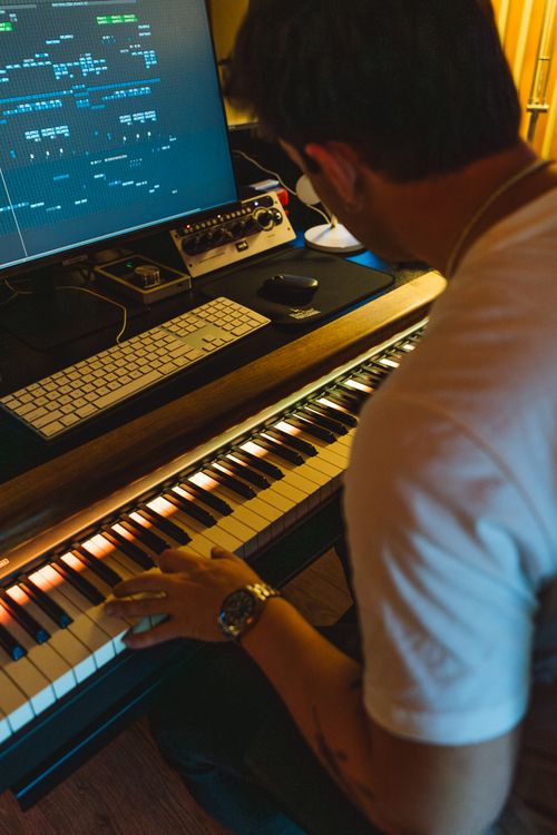 Free Musician creating music using a keyboard and computer setup in a studio environment. Stock Photo