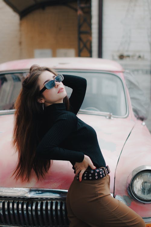 Model in Sunglasses and Sweater Posing by Vintage Car