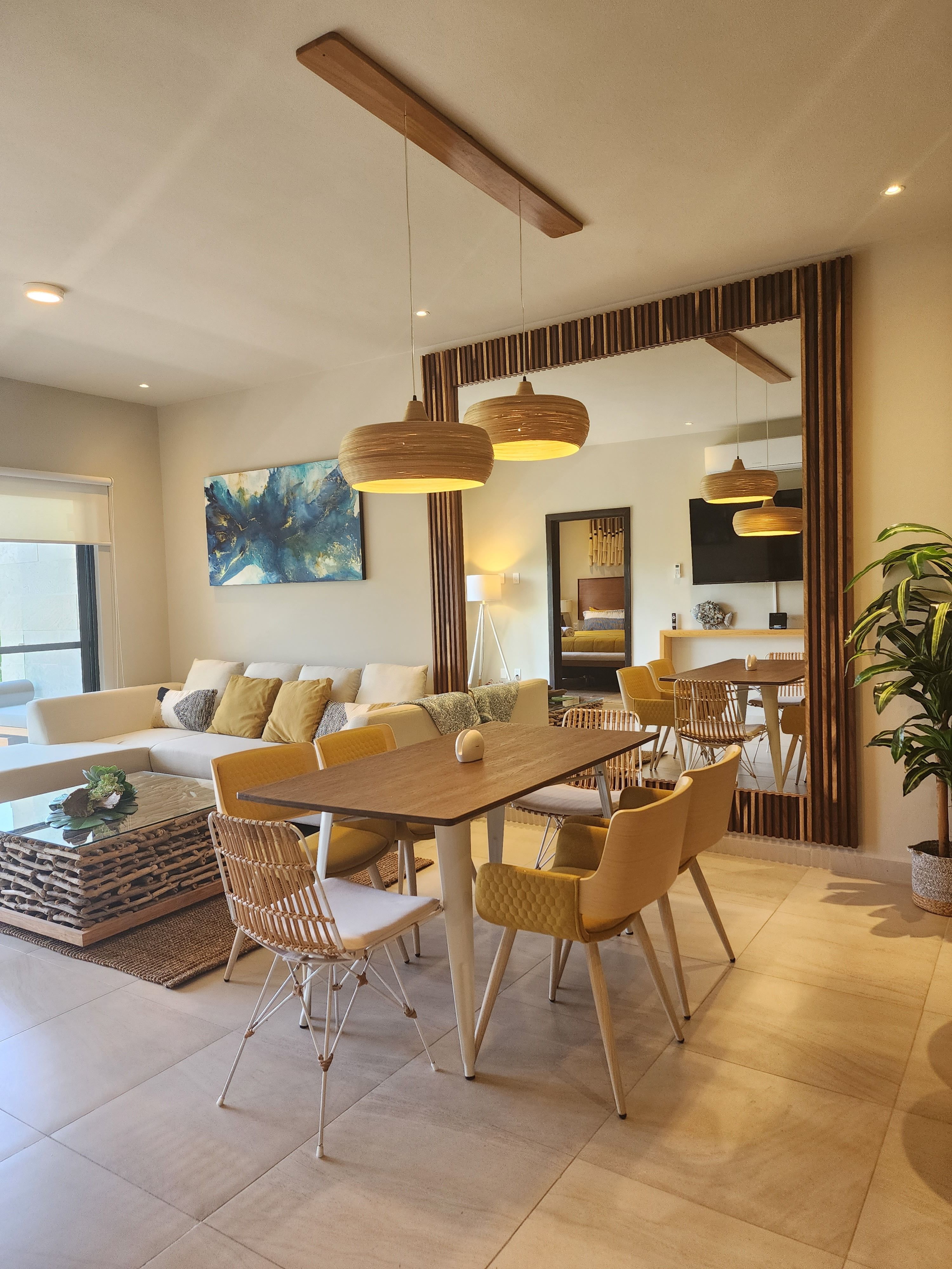 Modern furnished apartment living room with natural light, tropical plants, and contemporary decor