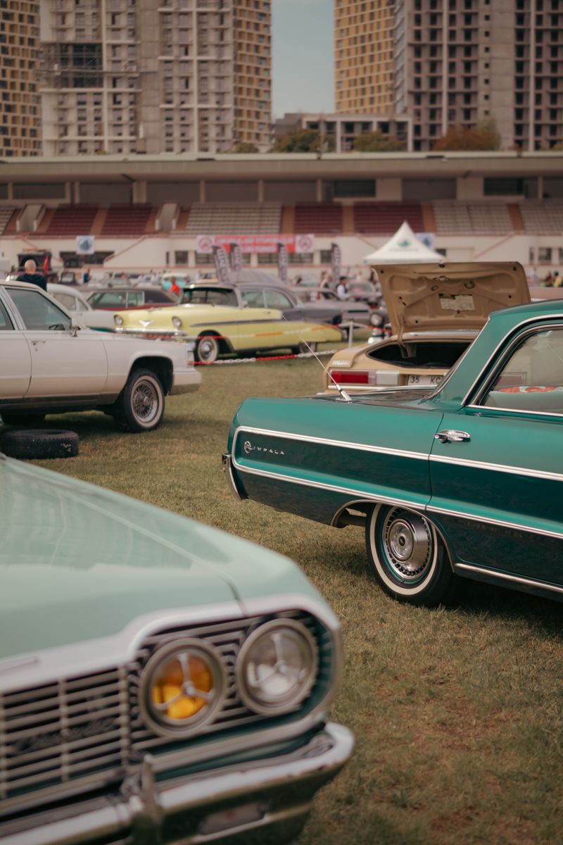 A classic car exhibition showcasing retro vehicles on a sunny day in an outdoor park setting.