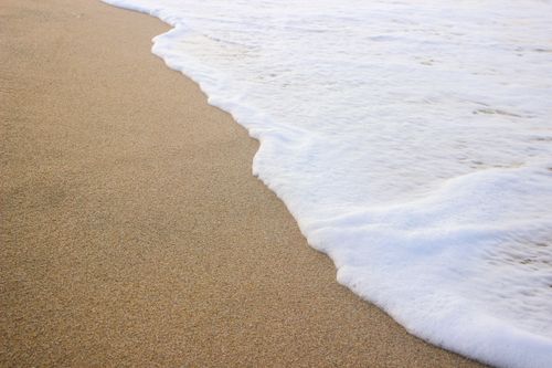 Free Tranquil scene of ocean waves gently lapping onto a sandy beach, perfect for relaxation. Stock Photo
