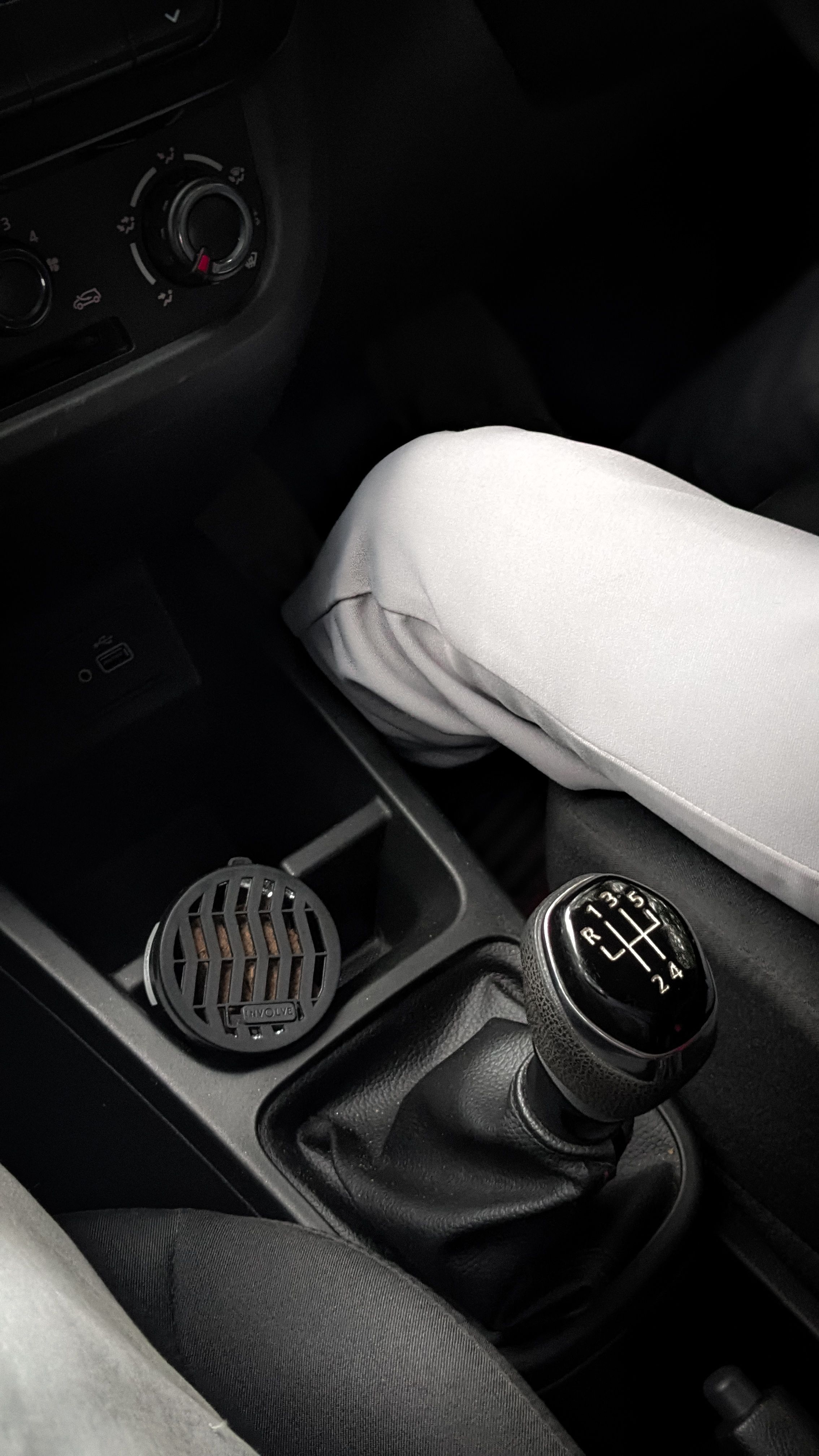 Close-up view of manual gearshift and car interior with a person sitting inside, showcasing details.