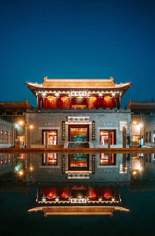 Illuminated Buddhist Temple with Pond in Evening
