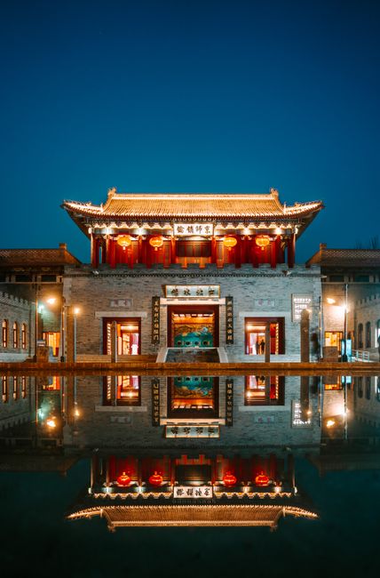 Stunning nighttime view of an illuminated traditional temple reflecting on a calm pond.