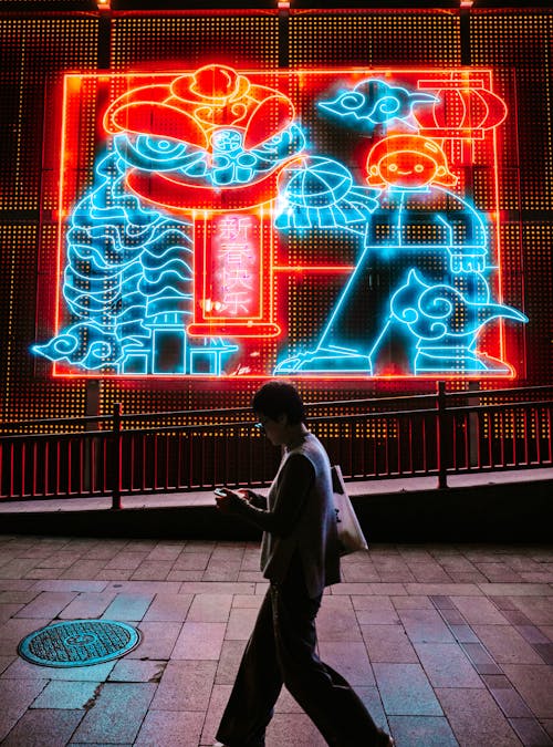 Woman Walking near Neon on Wall at Night