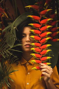 绿树成荫的花园里，一位年轻女子手里拿着充满活力的热带花卉