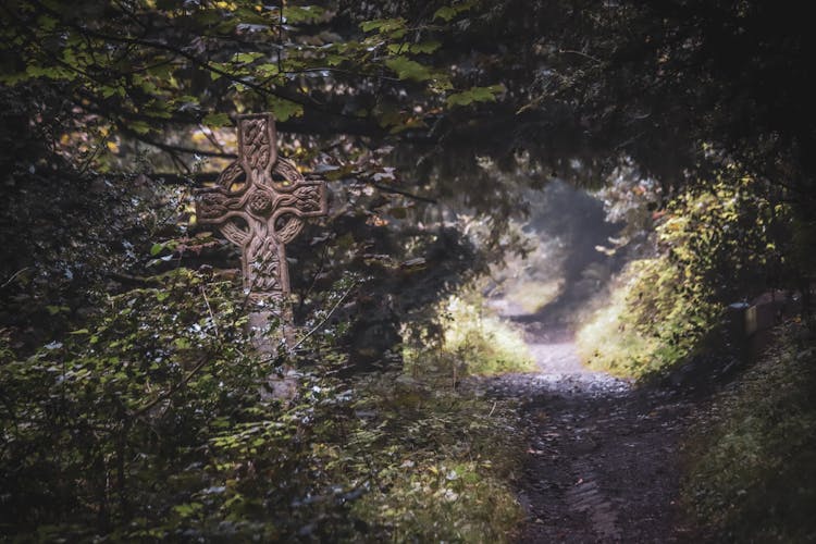 Ornately Carved Celtic Stone Cross On A Side Of A Forest Trail