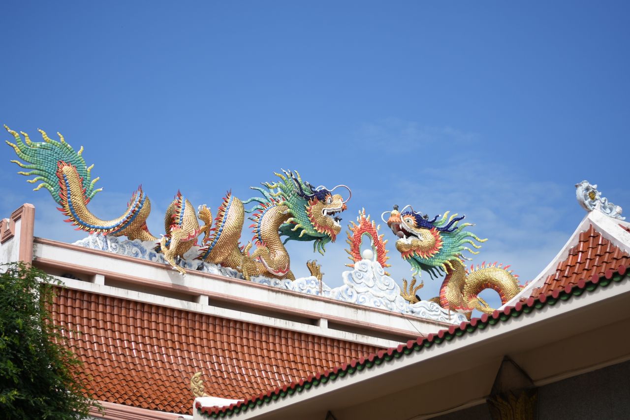 colorful dragon sculptures adorn the roof of a thai temple under a cle