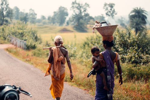 Free Two women and a child walk along a road in a rural landscape, reflecting traditional lifestyles. Stock Photo
