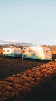 Two vintage trailers in the arid desert landscape of Taos, New Mexico, at sunset.