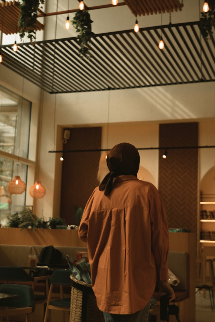 Back View Of A Woman Holding A Camera Walking In A Modern Building 