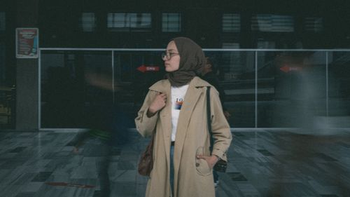 Free A young woman in a hijab stands in a busy station entrance, captured with motion blur. Stock Photo