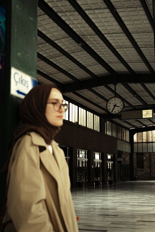 Woman in a Trench Coat Standing on a Platform at the Station 