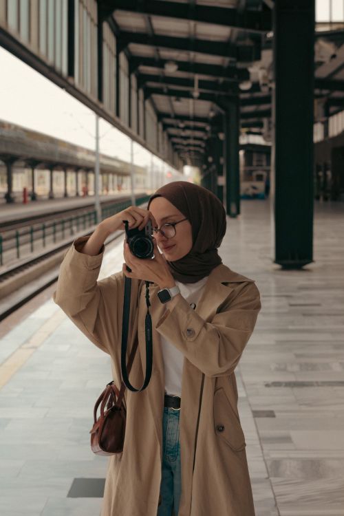 Free A young woman in a hijab takes photos at an urban railway station. Stock Photo