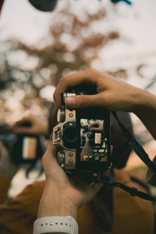 Free Hands holding a vintage camera capturing a close-up shot outdoors. Stock Photo