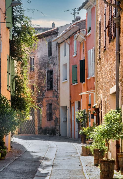 Free Scenic view of a narrow cobblestone street lined with colorful townhouses in a European town. Stock Photo