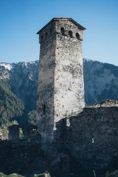 在风景如画的山间背景下，一座历史悠久的石塔矗立在蔚蓝的天空下