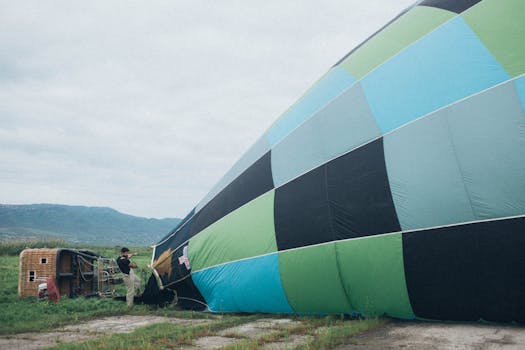 A man inflating a colorful hot air balloon in an open landscape preparing for flight.