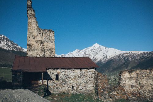 Free Ruined stone building against a backdrop of snow-capped mountains under a clear blue sky. Stock Photo