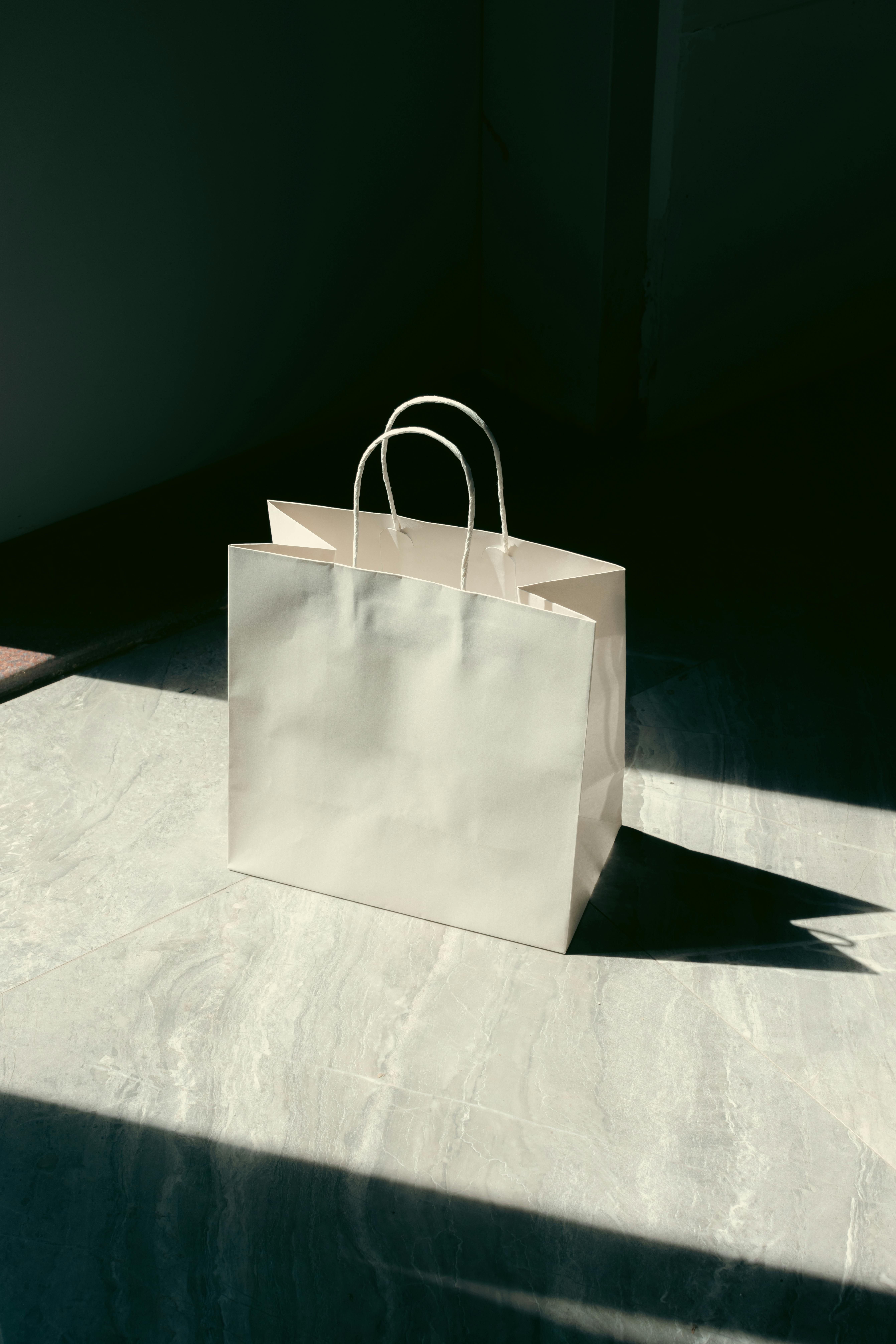 A single shopping bag illuminated by sunlight on a marble floor indoors.