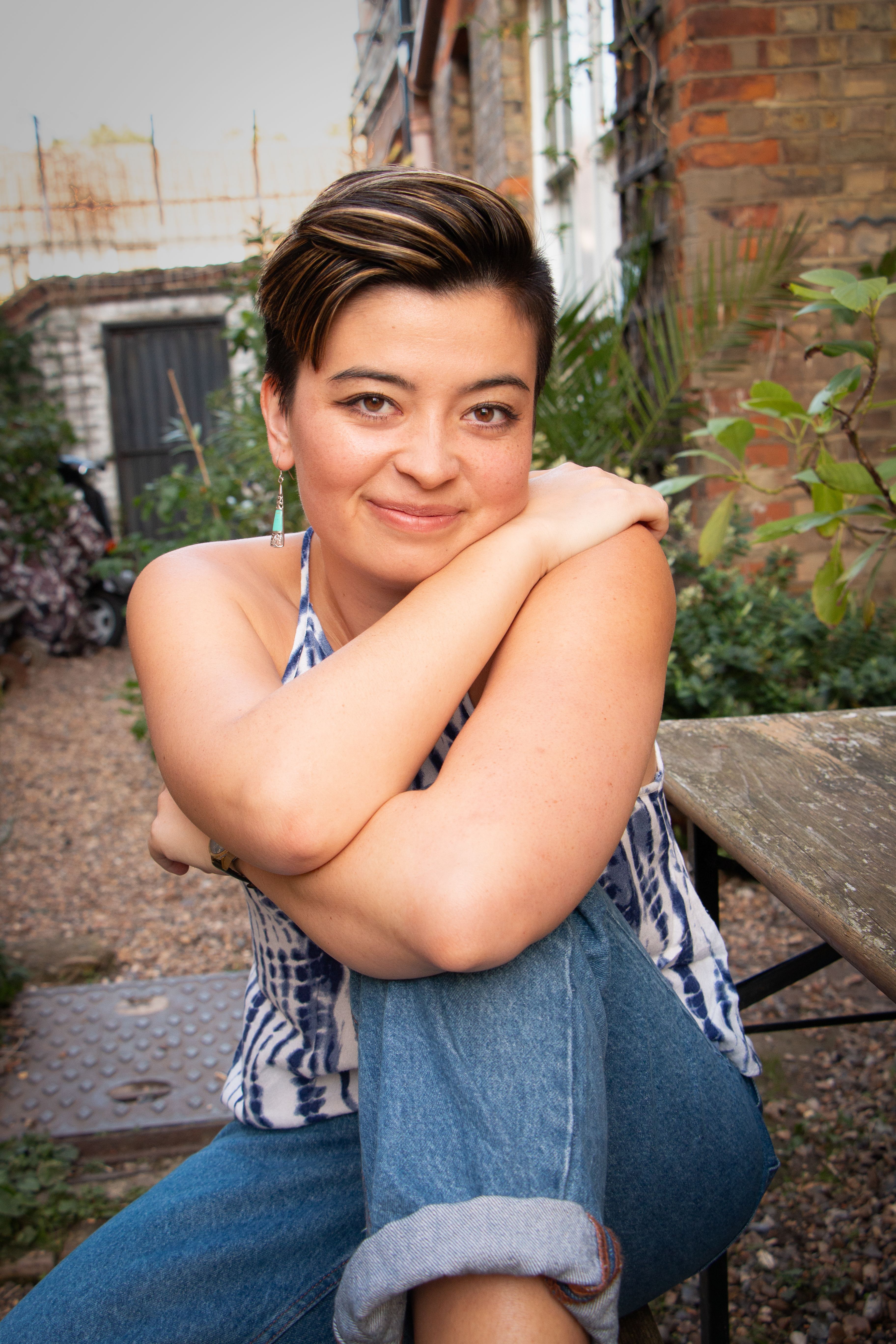 Smiling woman sitting comfortably in an outdoor London garden setting.