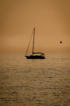 A silhouette of a sailboat during a golden sunset over Istanbul's tranquil waters.