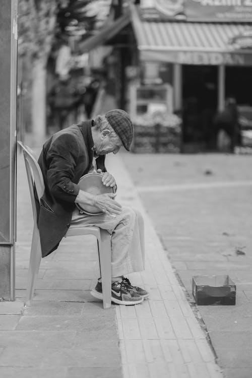 Elderly Street Musician Sitting on Sidewalk in Black and White