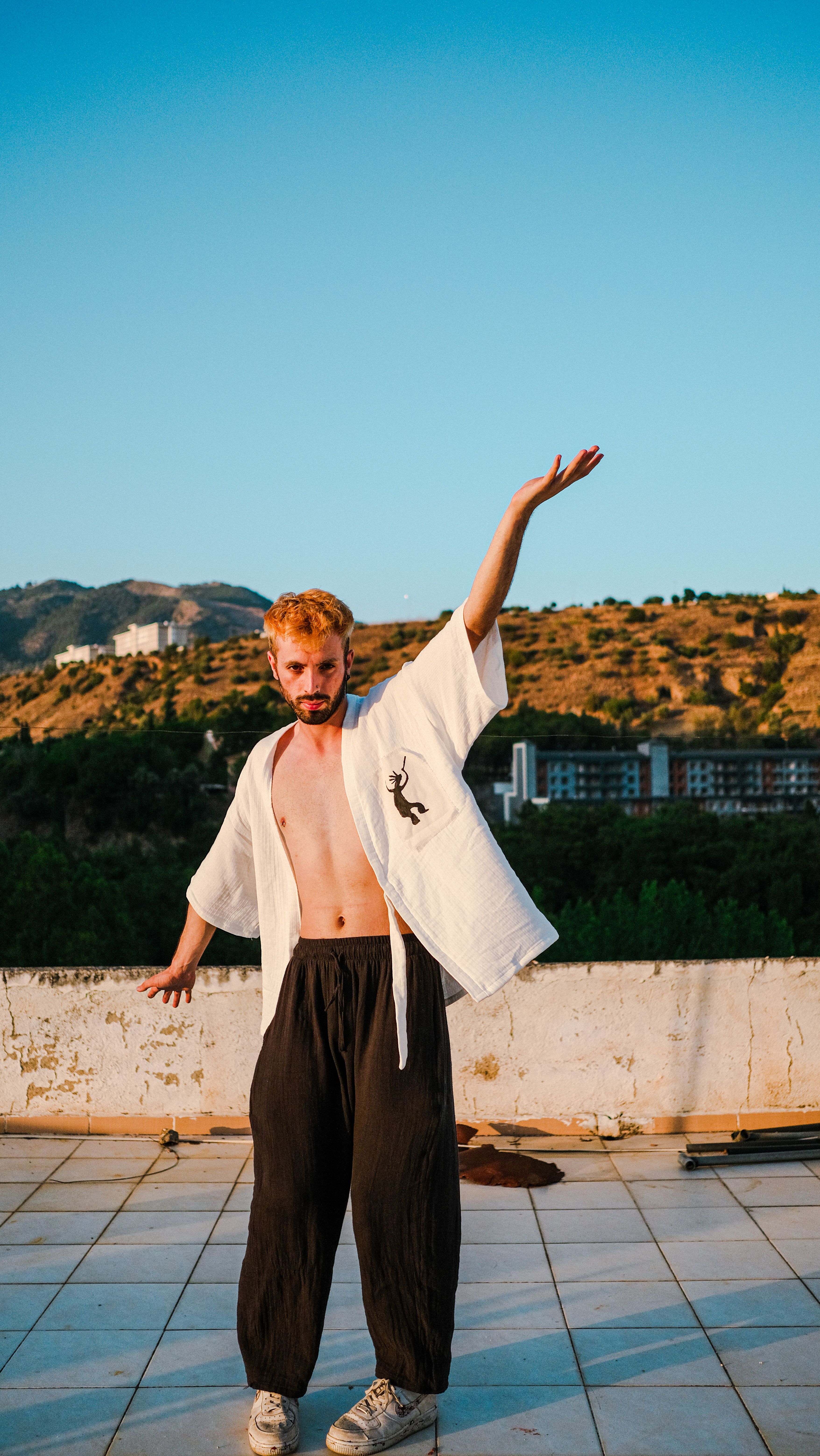 A captivating image of a young man posing with raised arm outdoors during sunset.