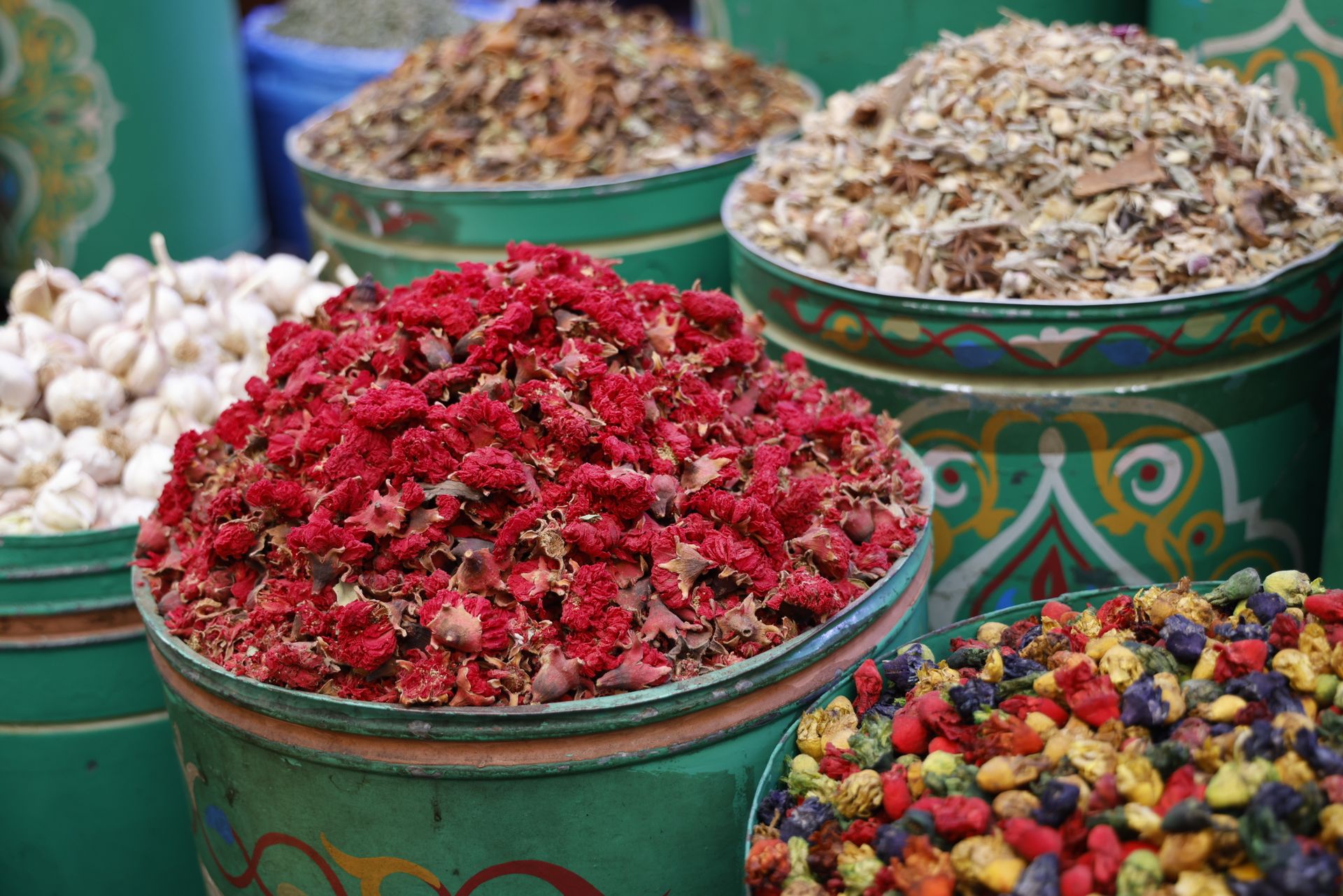Vivid display of dried flowers and herbs in vibrant market bins, showcasing a rich variety of spices