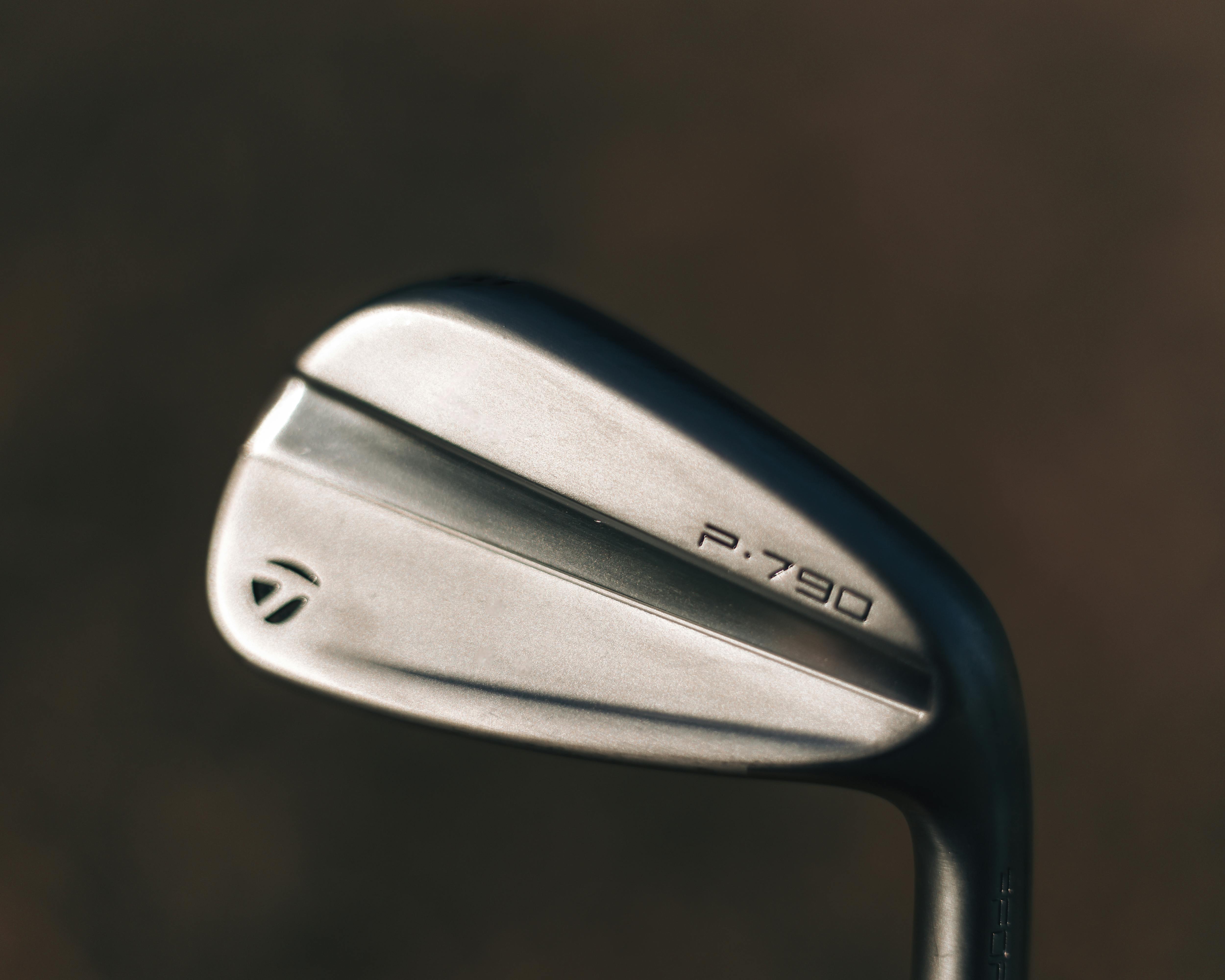 Detailed view of a P.790 golf iron showcasing its sleek silver design against a neutral background.