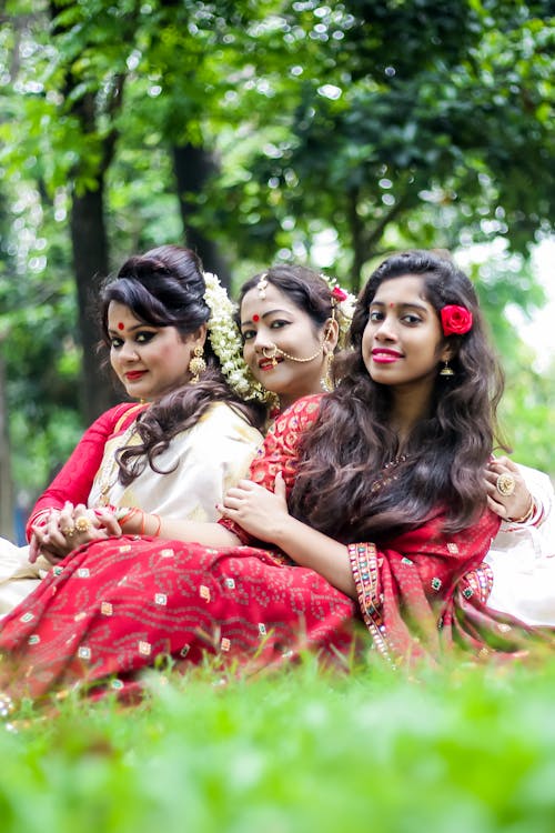Three Young Brunettes Wearing Saris Sitting together on the Grass
