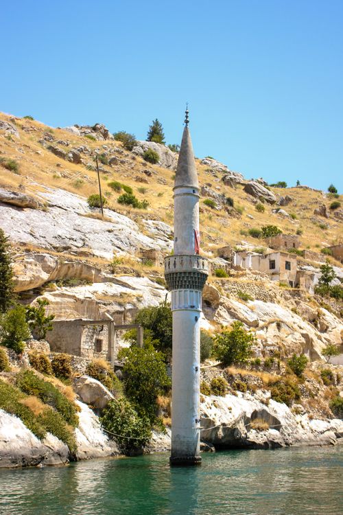 Free Photograph of a submerged minaret in the tranquil waters of Halfeti, Turkey, under a clear blue sky. Stock Photo